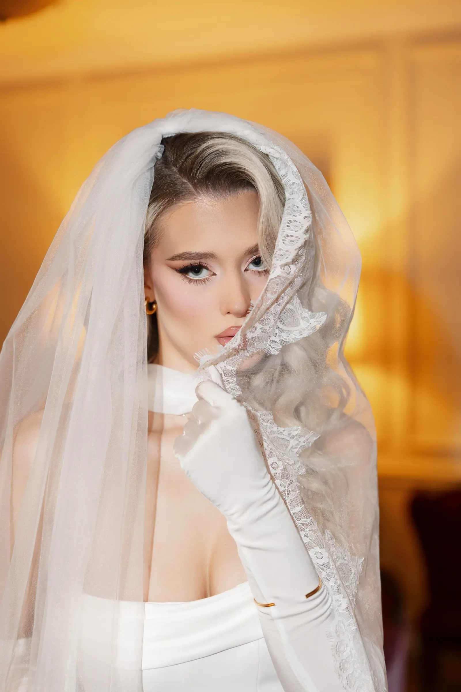 Portret editorial al unei modele blonde purtând voal și mănuși albe